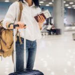 woman backpacker holding passport and map with suitcase standing